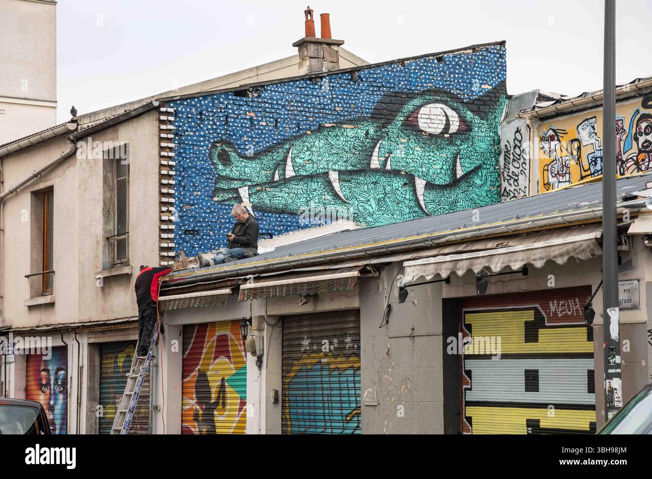Graffiti murali a coccodrillo e uomini al lavoro a Marché aux puces de Saint-Ouen-sur-Seine, Francia Foto Stock