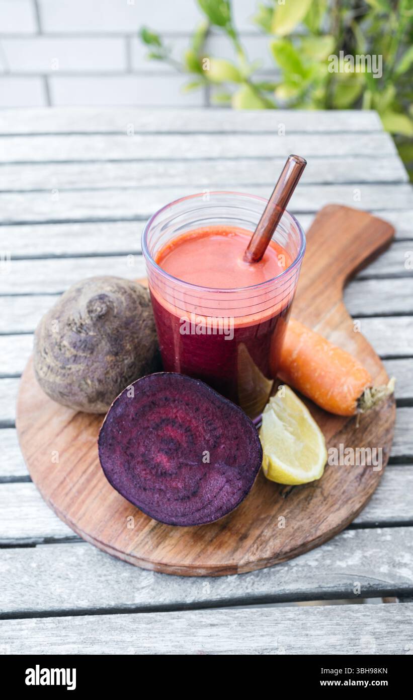 Un frullato vivace a base di barbabietola, carote e limone servito in un bicchiere trasparente. Ricca di antiossidanti e nutrienti, questa bevanda colorata supporta l'auto Foto Stock