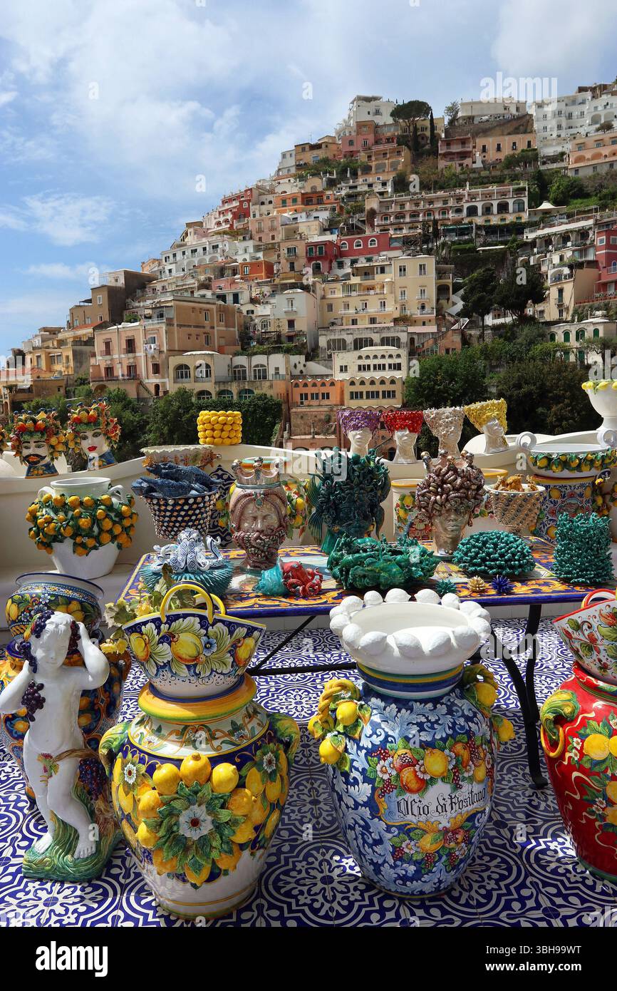 Esposizione all'aperto di colorate ceramiche fatte a mano a Positano con uno sfondo di case costruite sopra la città. Maggio '25 Costiera Amalfitana, Campania Italia Foto Stock