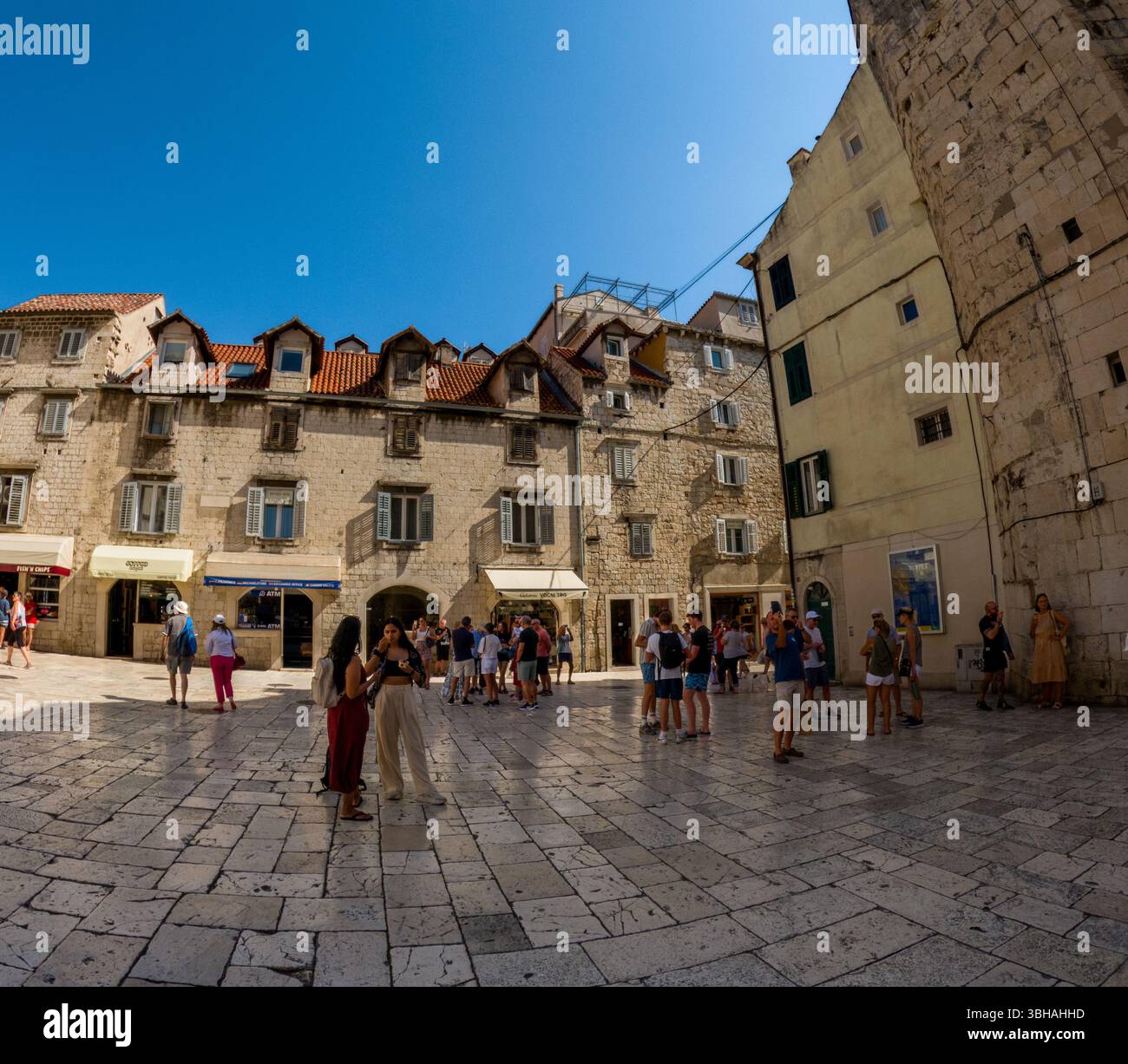 Spalato, Croazia - 8 settembre 2023: I turisti si riuniscono in una piazza vicino a negozi ed edifici storici, godendosi la giornata di sole ed esplorando la città. Foto Stock
