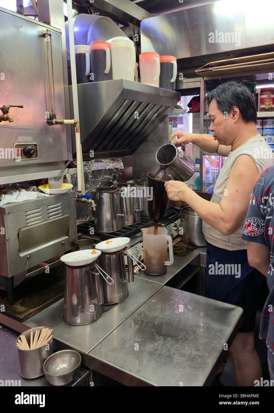 Preparare il tè al latte in stile HK al LAN Fong Yuen è una famosa casa di tè al latte in stile Hong Kong in Gage Street a Hong Kong. Foto Stock