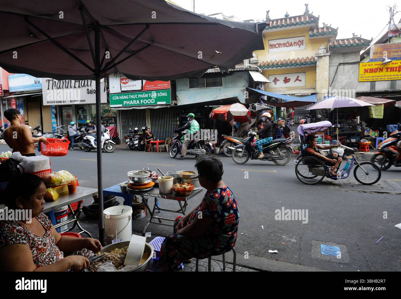 Ho chi Minh City, Vietnam - 12 dicembre 2022: I venditori di Street food aspettano i clienti in una strada di Saigon. Foto Stock