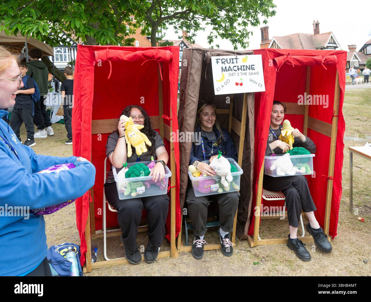 Tre donne che formano un gioco di macchine per la frutta umana al villaggio Summer fete, Bawdsey, Suffolk, Inghilterra, Regno Unito Foto Stock