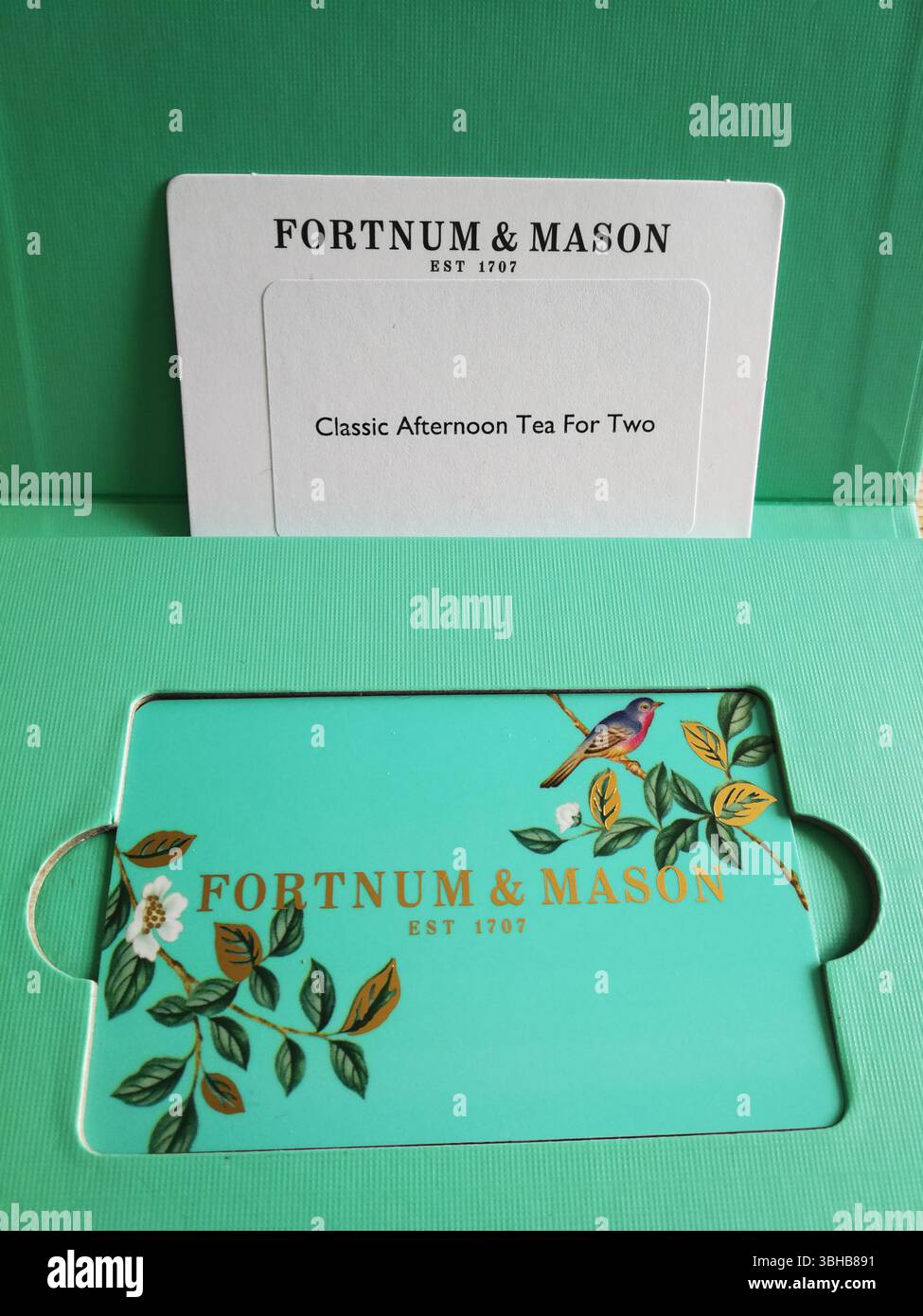 Elegante pacchetto tè pomeridiano Fortnum & Mason su sfondo color acqua. Londra, Regno Unito Foto Stock