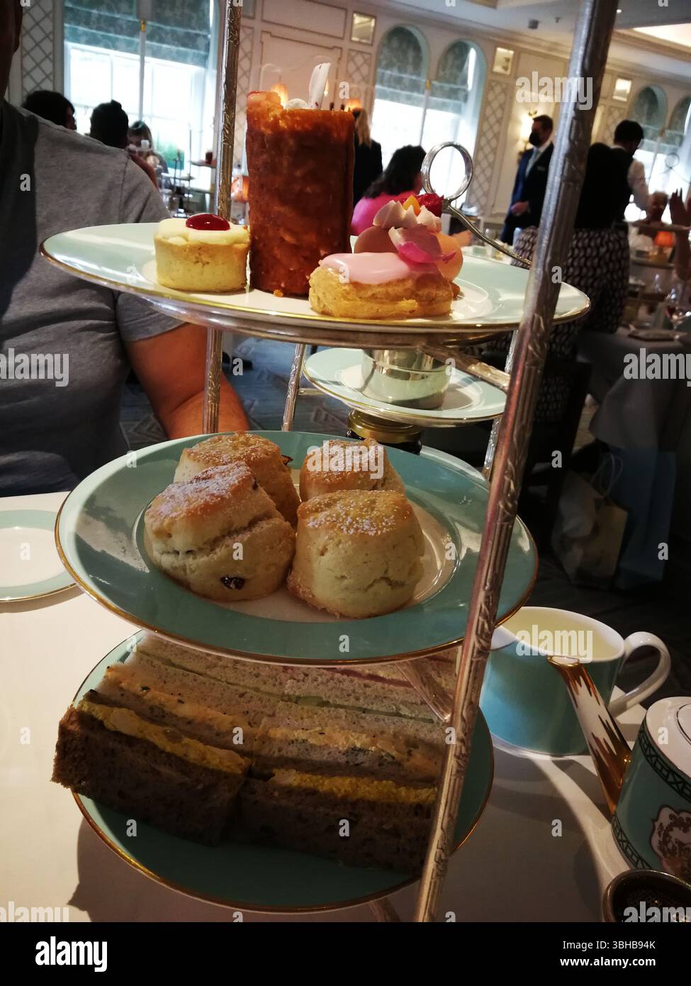 Elegante tè pomeridiano con panini, focaccine e dessert assortiti in un ambiente di lusso. Londra, Regno Unito Foto Stock