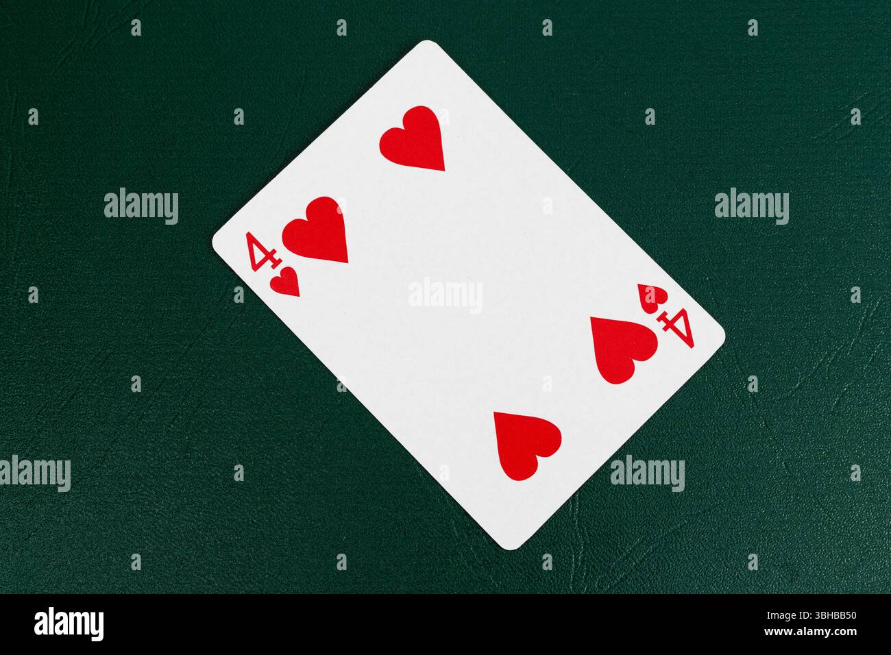 Quattro di cuori che giocano a carte su Green Poker Table Foto Stock