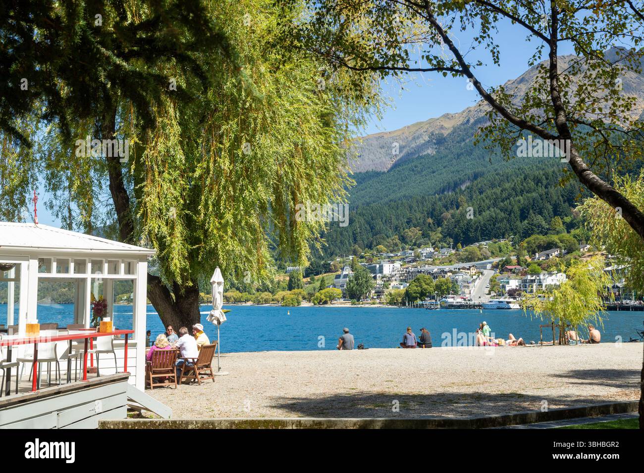 Persone che si godono una giornata di sole sulla spiaggia della baia di Queenstown sulle rive del lago Wakatipu, Queenstown, Otago, nuova Zelanda Foto Stock