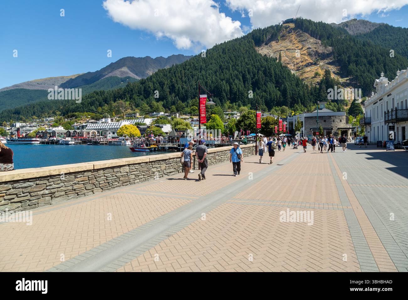 Persone che camminano lungo Marine Parade che si affaccia sulla spiaggia di Queenstown e sul lago Wakatipu, Otago, nuova Zelanda Foto Stock