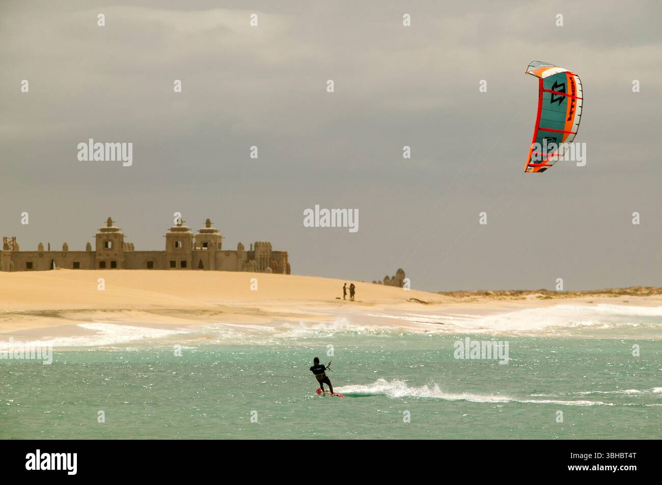 Kiteboarder kiting vicino a un resort costruito a metà sull'isola di Sal, Capo Verde Foto Stock