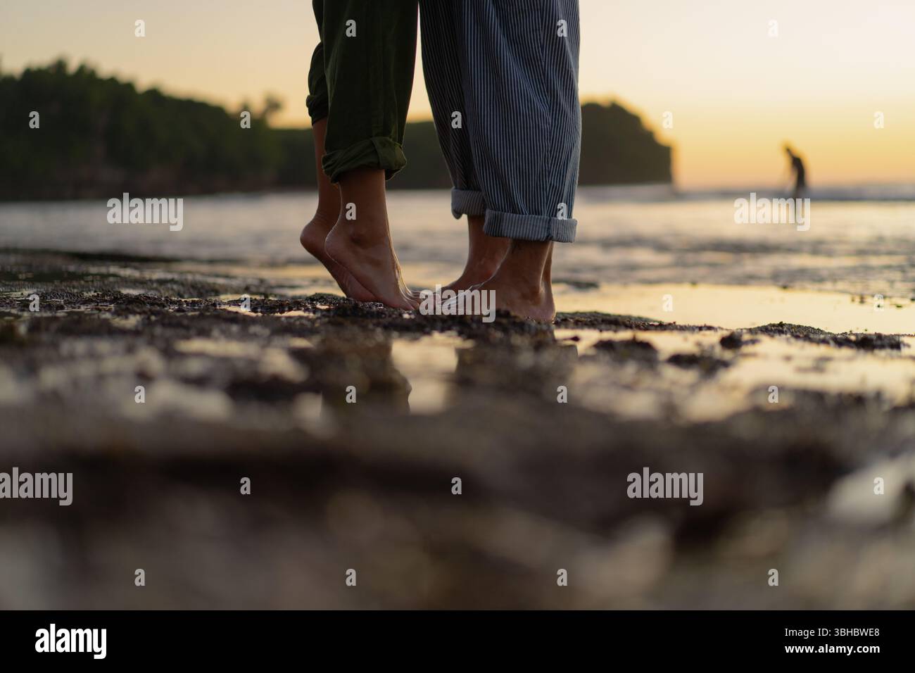 Coppia a piedi nudi in piedi vicini sulla spiaggia al tramonto Foto Stock