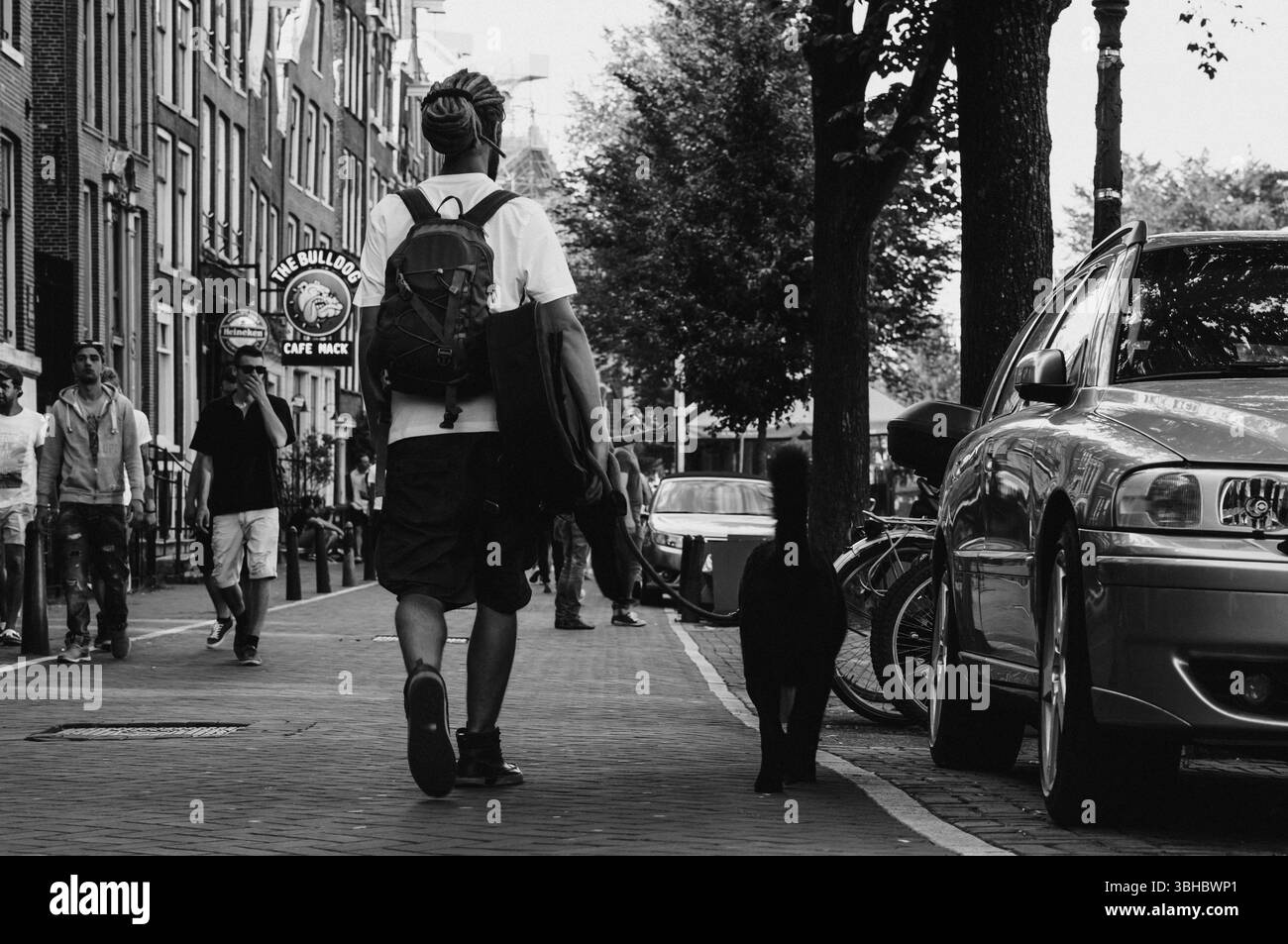 Uomo con cane che cammina per la strada di Amsterdam, foto in bianco e nero Foto Stock