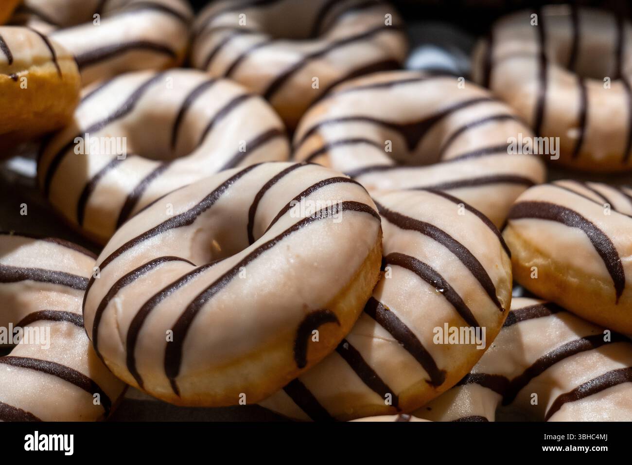 Dolce delizia deliziose ciambelle glassate con strisce di cioccolato. Foto Stock