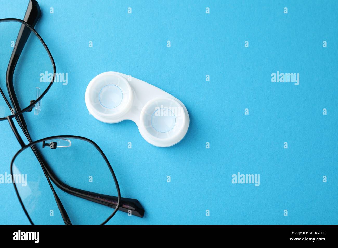Lenti a contatto in astuccio e occhiali su sfondo blu, piatto. Spazio per il testo Foto Stock