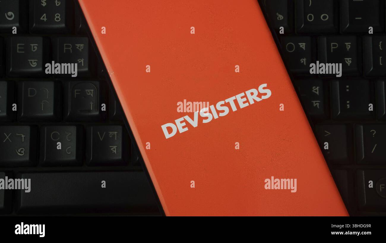Dispositivo arancione con logo DEVSISTERS sullo sfondo della tastiera Foto Stock