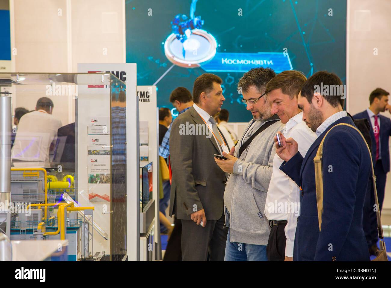 mosca, russia, 28.06.2017 Un gruppo di uomini sta guardando un'esposizione di un prodotto. Un uomo sta guardando il suo telefono Foto Stock