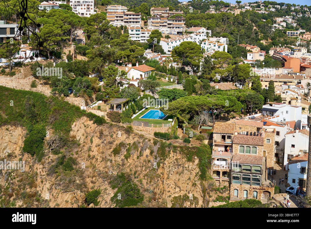 Una splendida vista di Tossa de Mar, che mostra edifici costieri annidati tra lussureggiante vegetazione e una piscina. Foto Stock