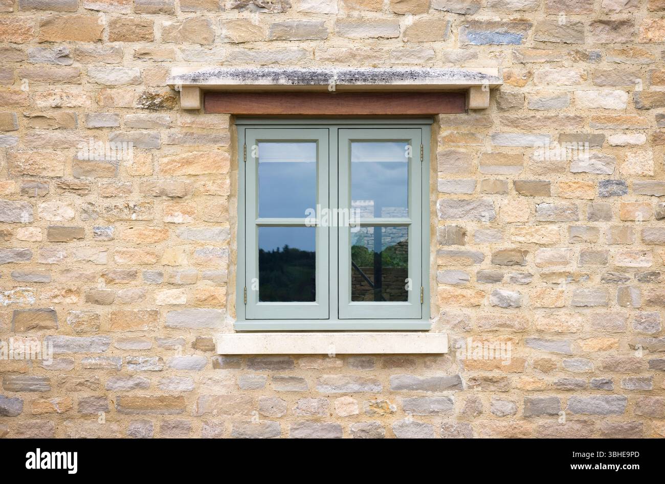 Finestra in legno dipinto di verde su un cottage in pietra Cotswold, Regno Unito Foto Stock