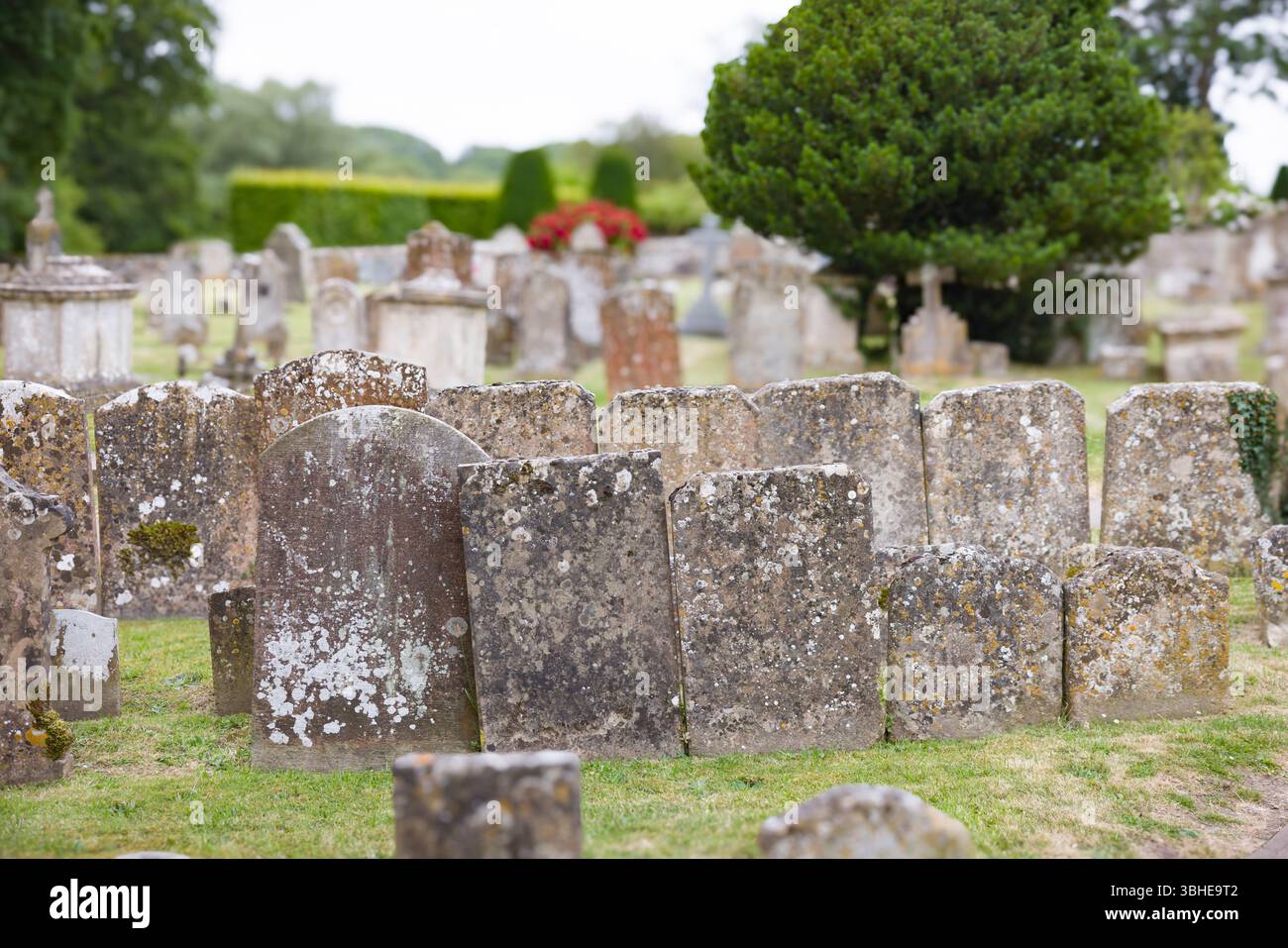 Antico cimitero inglese con lapidi intemperie ricoperte di muschio e licheni. Tranquillo cimitero rurale, Regno Unito. Nessuna lapide identificabile. Foto Stock