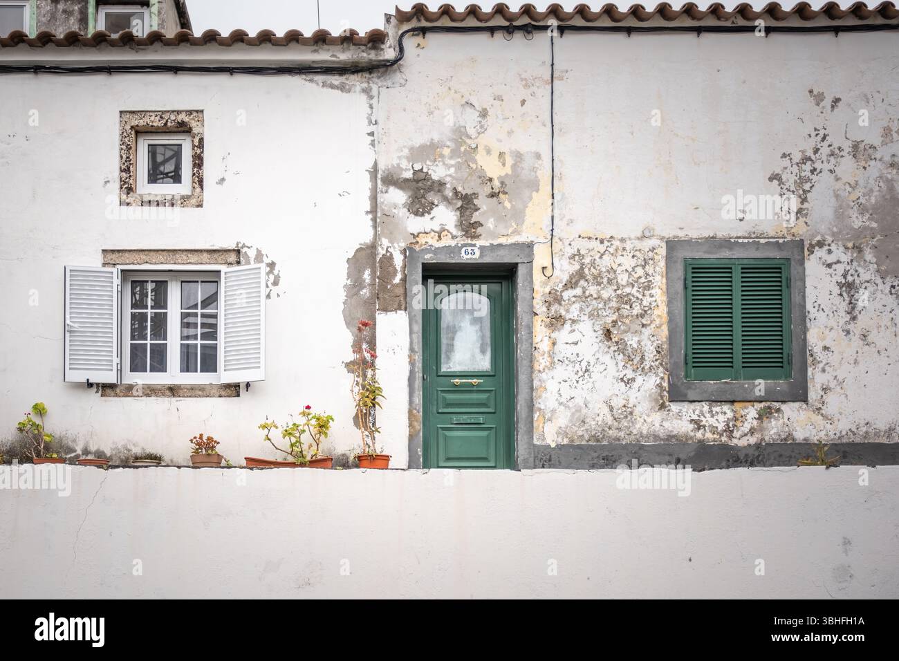 Facciata del vecchio edificio europeo con porta verde e tapparelle - architettura rustica Foto Stock