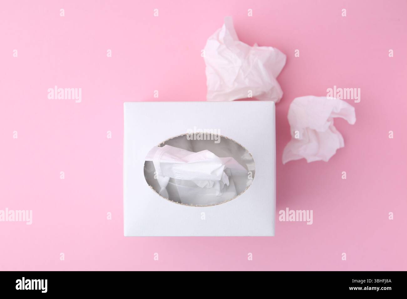 Scatola con fazzoletti di carta e fazzoletti su sfondo rosa, piatto Foto Stock