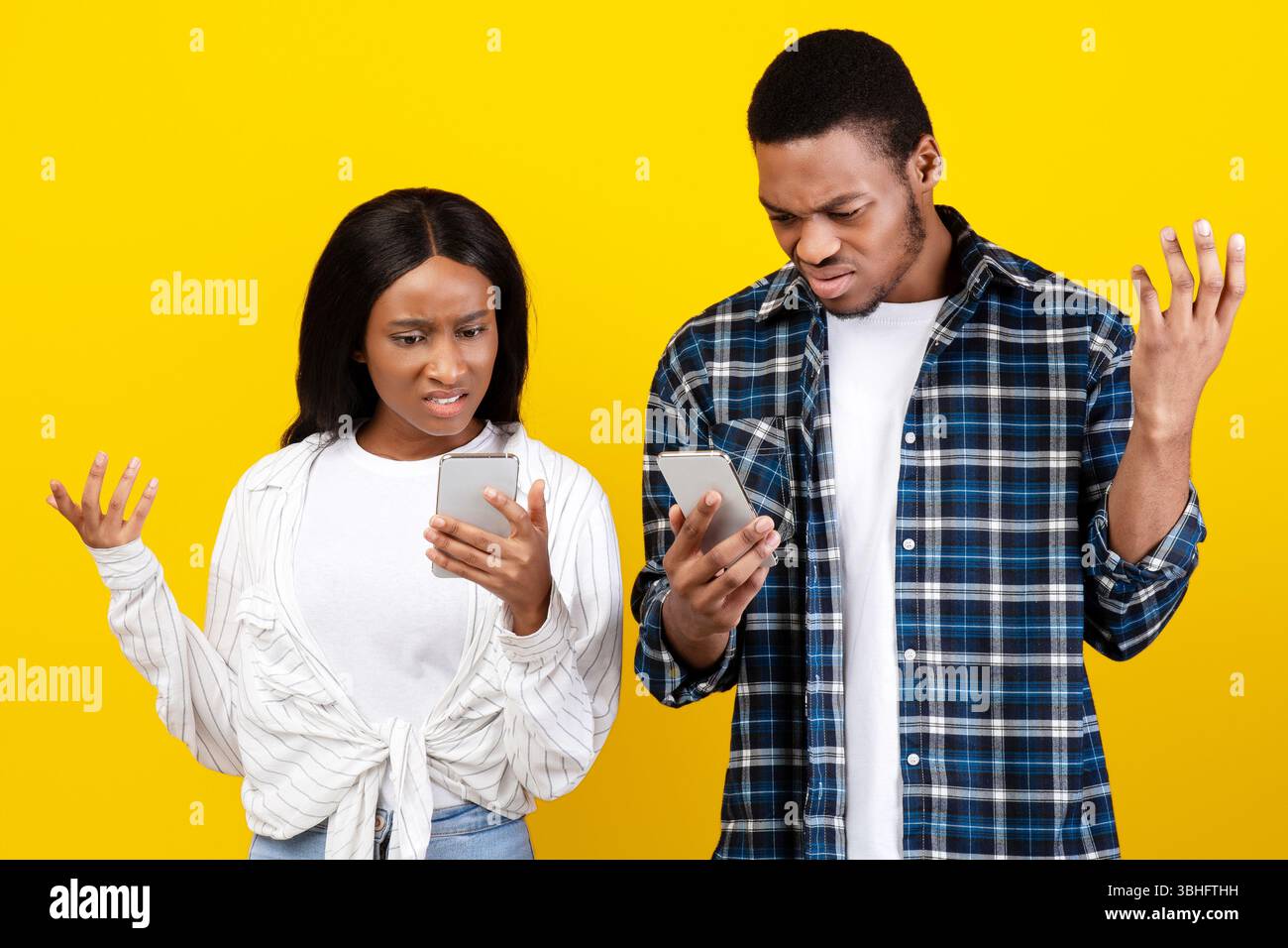 Sorpresa triste millennial african american coppia guardando telefoni con aprite le bocche e alzate le mani Foto Stock