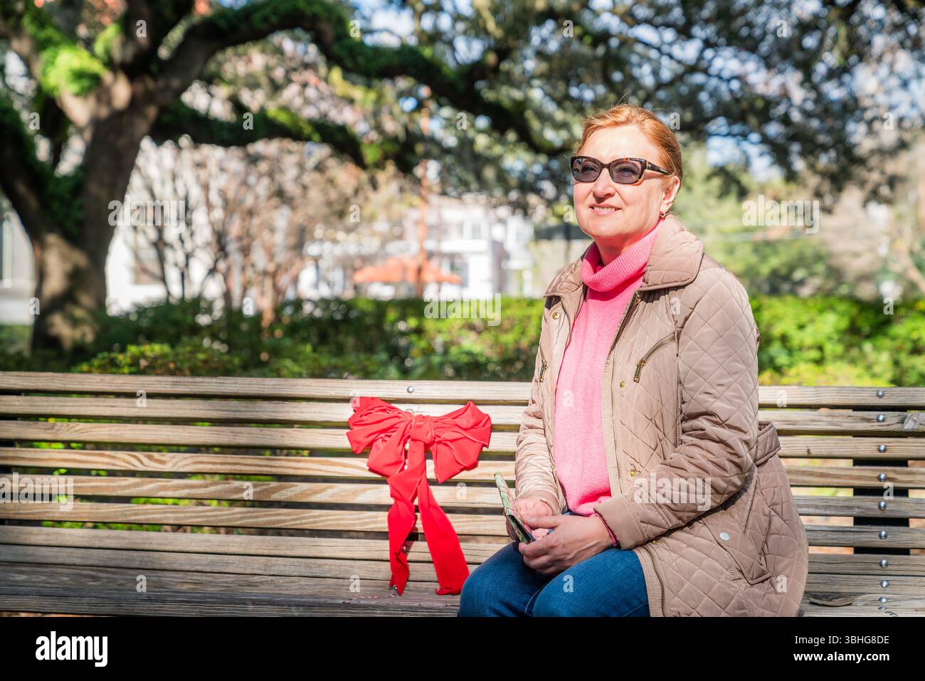 Una bella donna matura seduta su una panchina in un parco cittadino di Savannah, Georgia Foto Stock