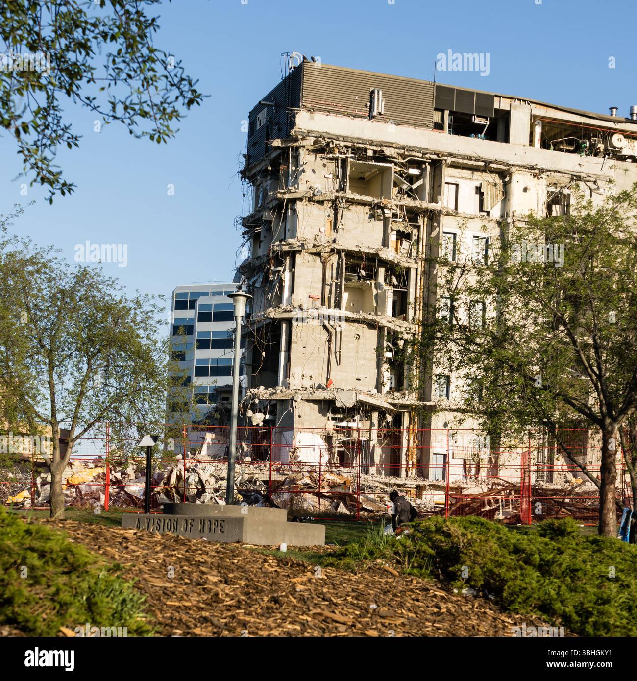 Edmonton, Canada, 2 maggio 2025: Piedistallo della scultura "A Vision of Hope" con progetto di abbattimento e demolizione del centro di detenzione sullo sfondo Foto Stock