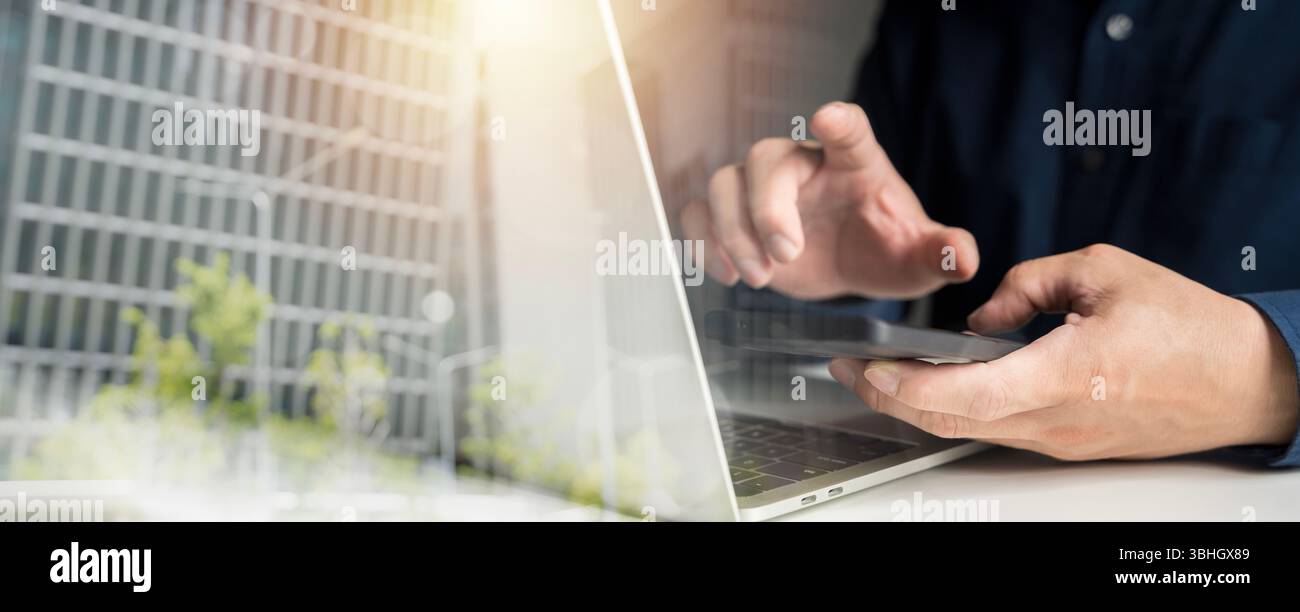Primo piano di mani maschili utilizzando smartphone e computer portatile alla moderna scrivania con riflesso urbano, concetto di comunicazione digitale, telecomando Foto Stock