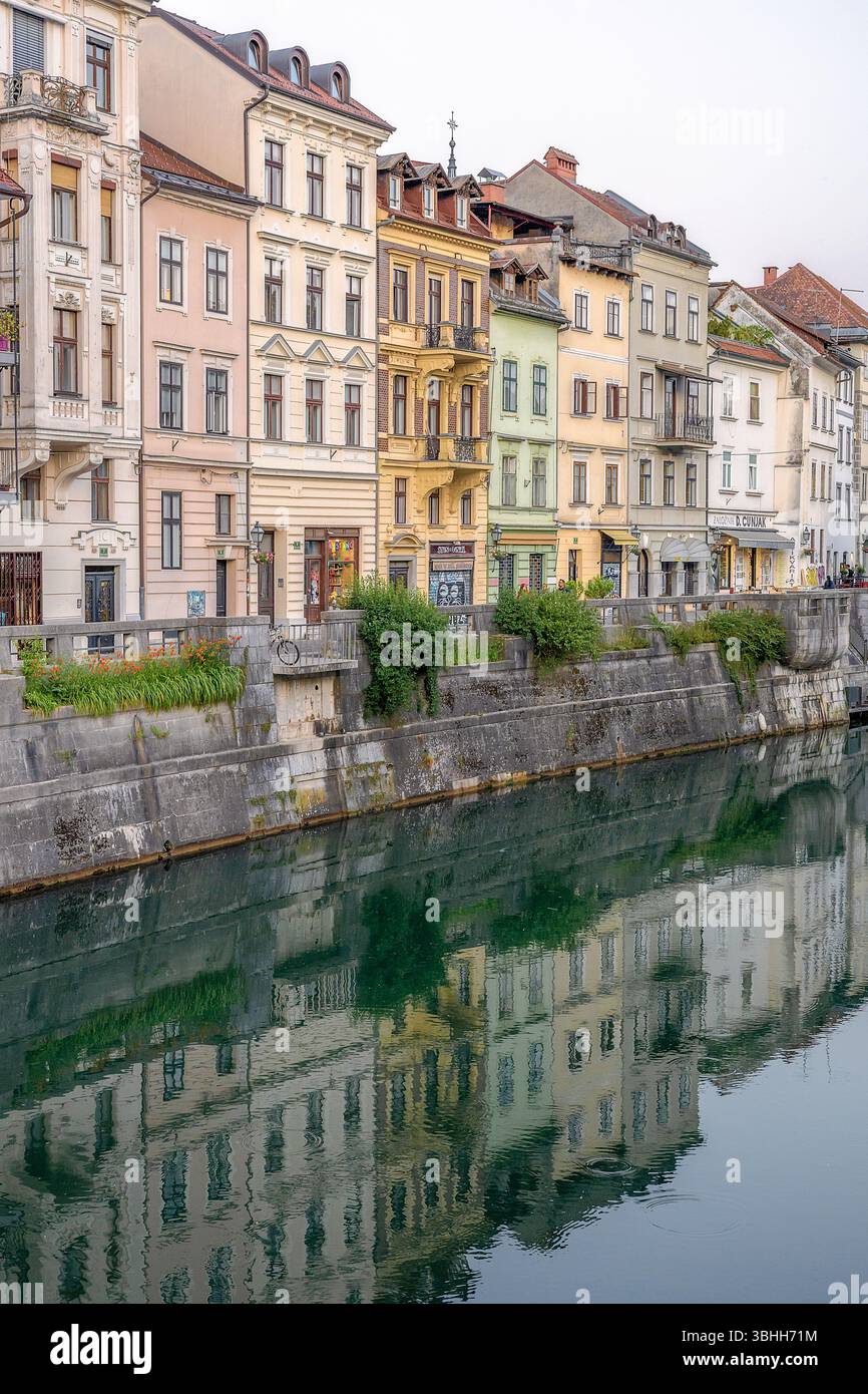 Case storiche colorate lungo il fiume Ljubljanica a Lubiana, Slovenia. Le affascinanti facciate si riflettono splendidamente sulle calme acque del fiume. Foto Stock