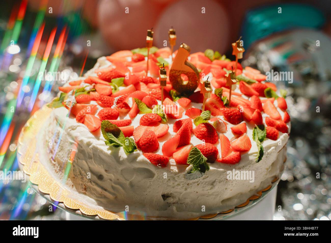 Torta celebrativa condita con fragole fresche e foglie di menta, con una candela numero sei, perfetta per una festa di sesta compleanno o un anniversario. Cap Foto Stock