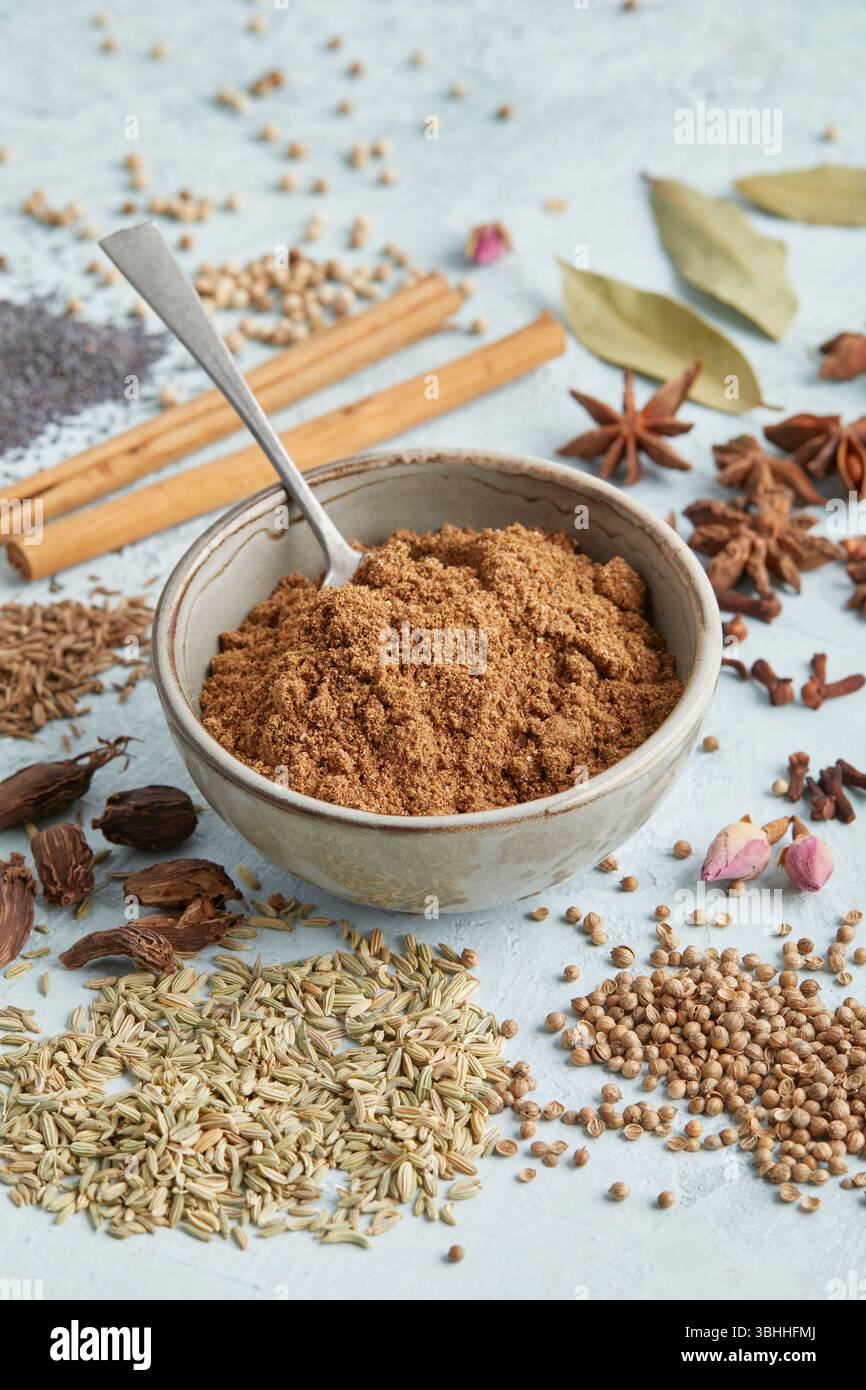 Masala al garam in una piccola ciotola circondata da spezie intere come anice stellato, cannella e chiodi di garofano, un audace mix di spezie indiane, perfetto per il cibo e il chai Foto Stock