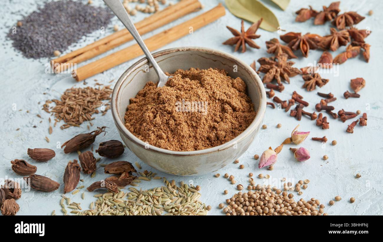 Masala al garam in una piccola ciotola circondata da spezie intere come anice stellato, cannella e chiodi di garofano, un audace mix di spezie indiane, perfetto per il cibo e il chai Foto Stock