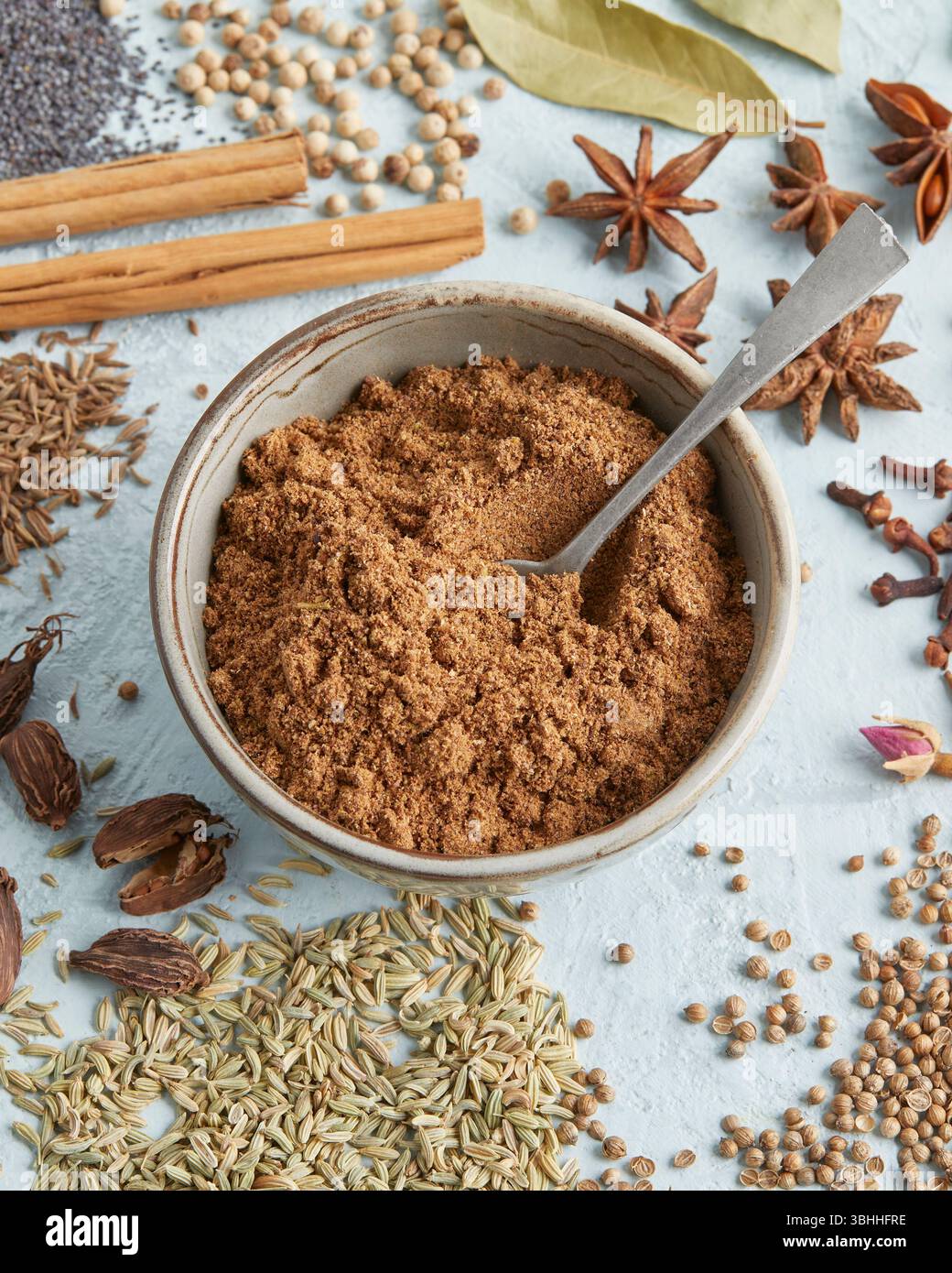 Masala al garam in una piccola ciotola circondata da spezie intere come anice stellato, cannella e chiodi di garofano, un audace mix di spezie indiane, perfetto per il cibo e il chai Foto Stock