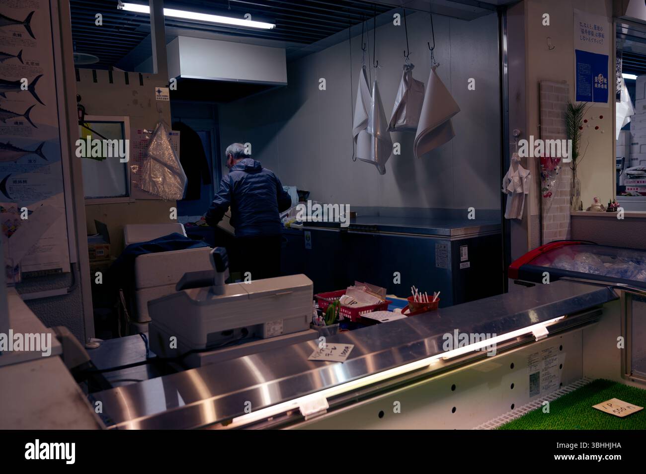Il pescivendolo solitario si riordina dopo una giornata di lavoro in un mercato alimentare Foto Stock