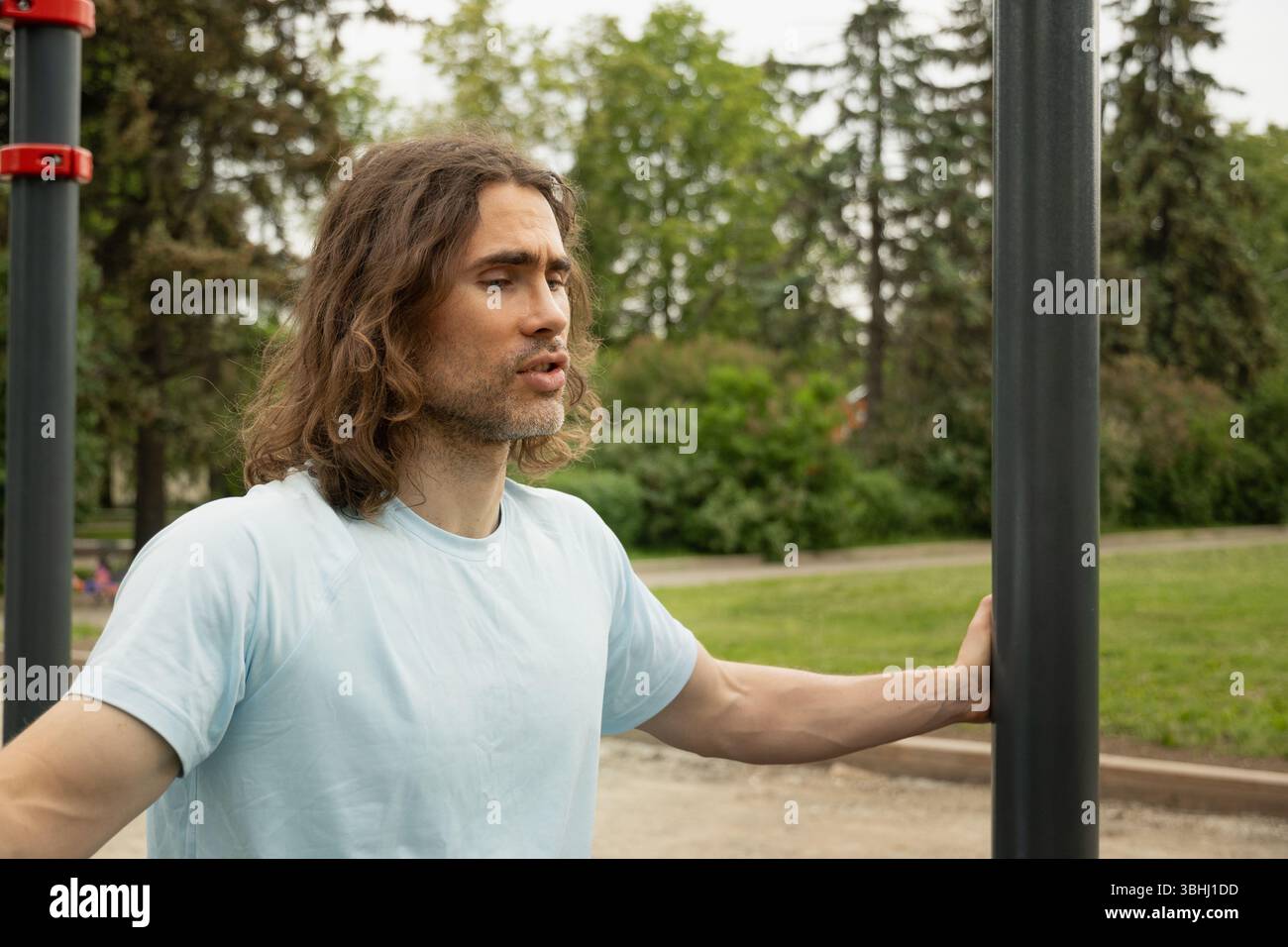 Ritratto di un uomo caucasico stanco e sportivo espressione premurosa, perso nel pensiero nel parco pubblico vicino alle attrezzature sportive. Pigrizia, si obbliga a farlo Foto Stock