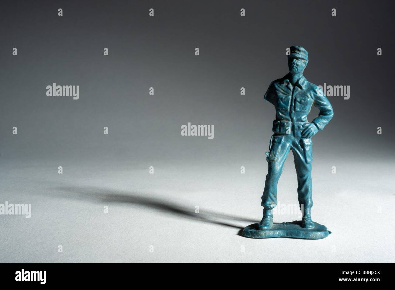 Un piccolo soldato giocattolo si erge in posizione verticale con una posa sicura. L'illuminazione soffusa crea un'incredibile interazione di ombre Foto Stock
