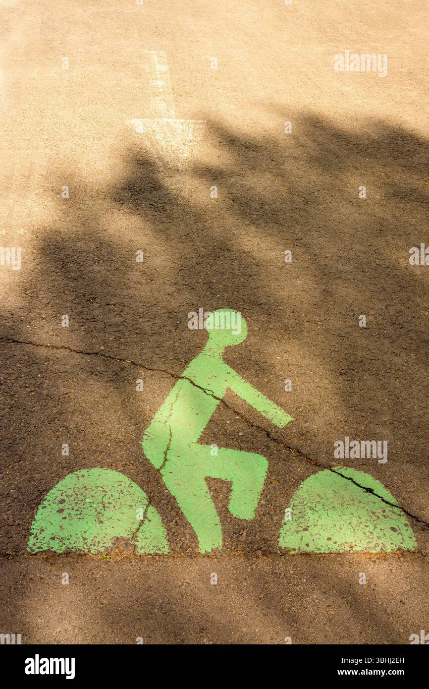 Una pista ciclabile verde è visibile su una strada della città, caratterizzata da una silhouette da ciclista. Foto Stock