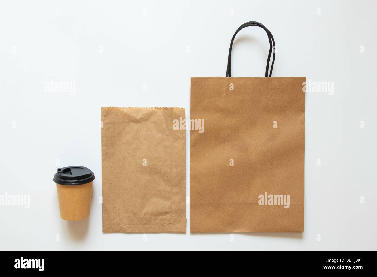 Sacchetti di carta e tazza da caffè con coperchio su sfondo bianco, mockup di confezioni per caffè da asporto e cibo, vista dall'alto Foto Stock