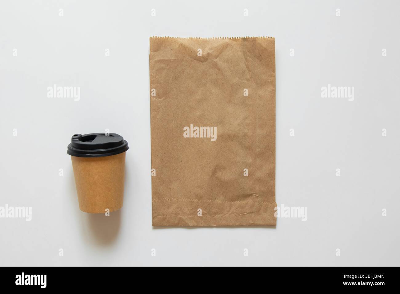 Sacchetto di carta e tazza da caffè con coperchio su sfondo bianco, mockup di confezionamento di caffè da asporto e alimenti, vista dall'alto Foto Stock