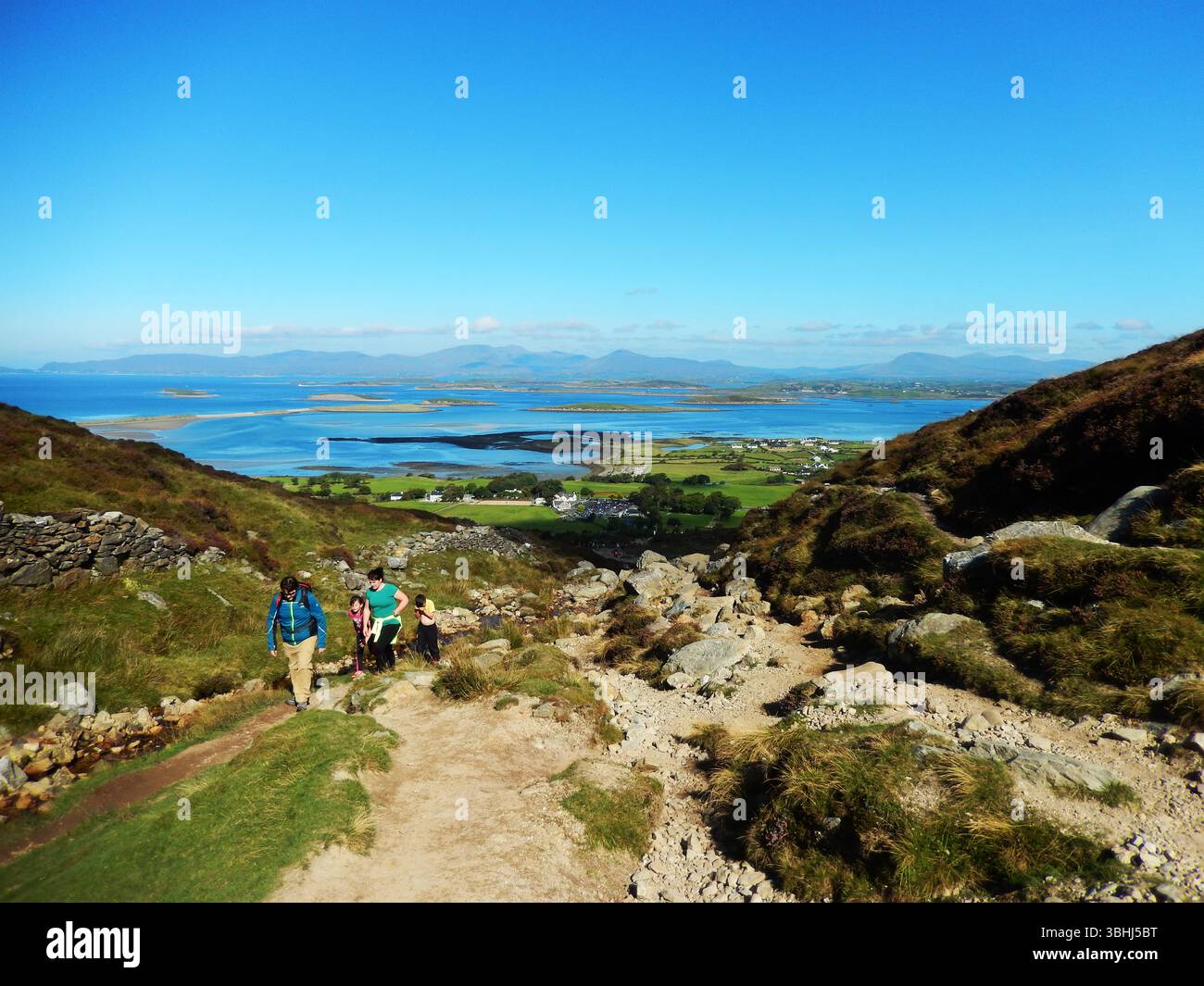 Sentiero in cima alla collina che si affaccia sul paesaggio costiero panoramico con isole e campi verdi Foto Stock