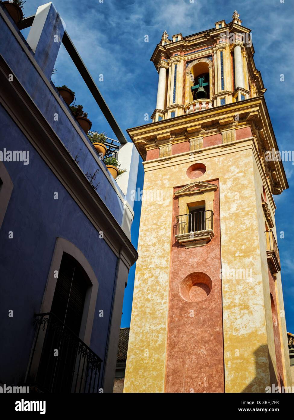 Il campanile di San Bartolomeo sorge sopra edifici colorati nello storico quartiere ebraico di Siviglia, evidenziando una splendida architettura. Foto Stock