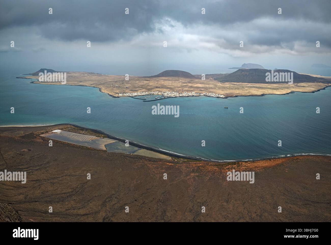 Vista panoramica dell'isola la Graciosa dalle scogliere della Famara a Lanzarote, mostrando le Salinas del Río (a Lanzarote), il villaggio di Caleta del Sebo Foto Stock