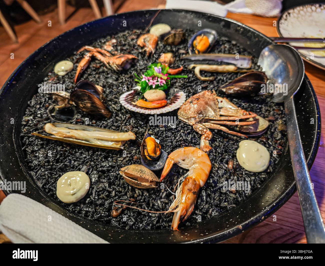 Gustate un delizioso piatto di riso nero cucinato con pesce assortito a Lanzarote, Isole Canarie, mettendo in risalto le tradizioni culinarie locali. Foto Stock