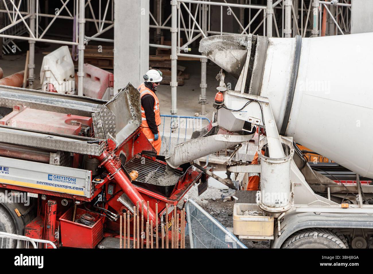 Operaio edile in attrezzature di sicurezza che gestisce betoniere in un cantiere affollato con impalcature sullo sfondo newcastle upon tyne Foto Stock