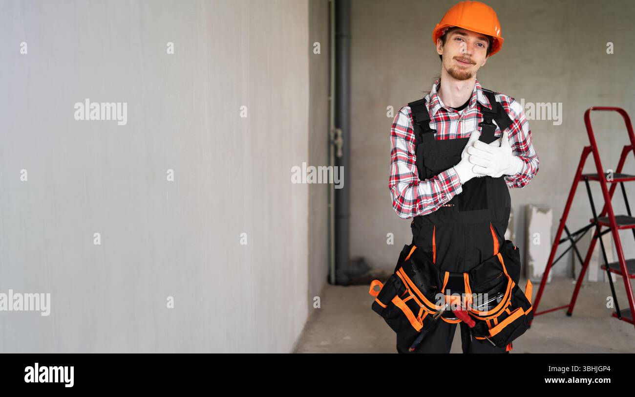 Giovane caposquadra o costruttore con le mani sul petto, con gesti grati sul viso Foto Stock