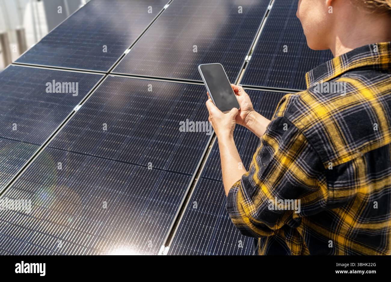 Lavoratore di manutenzione che controlla le prestazioni dei pannelli solari sullo smartphone Foto Stock
