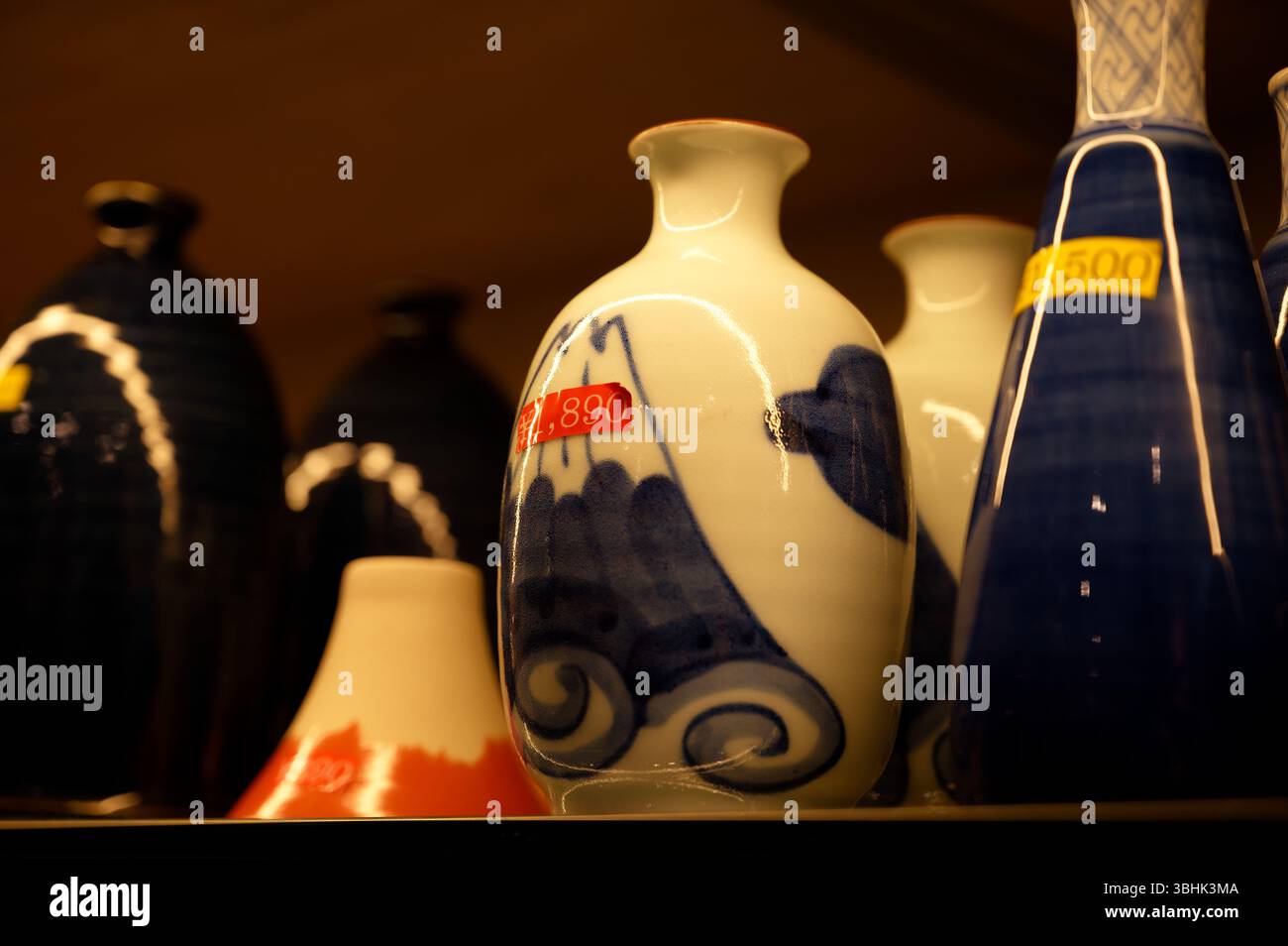 Esposizione di bottiglie di sake dipinte a mano con il Monte Fuji e motivi tradizionali giapponesi Foto Stock