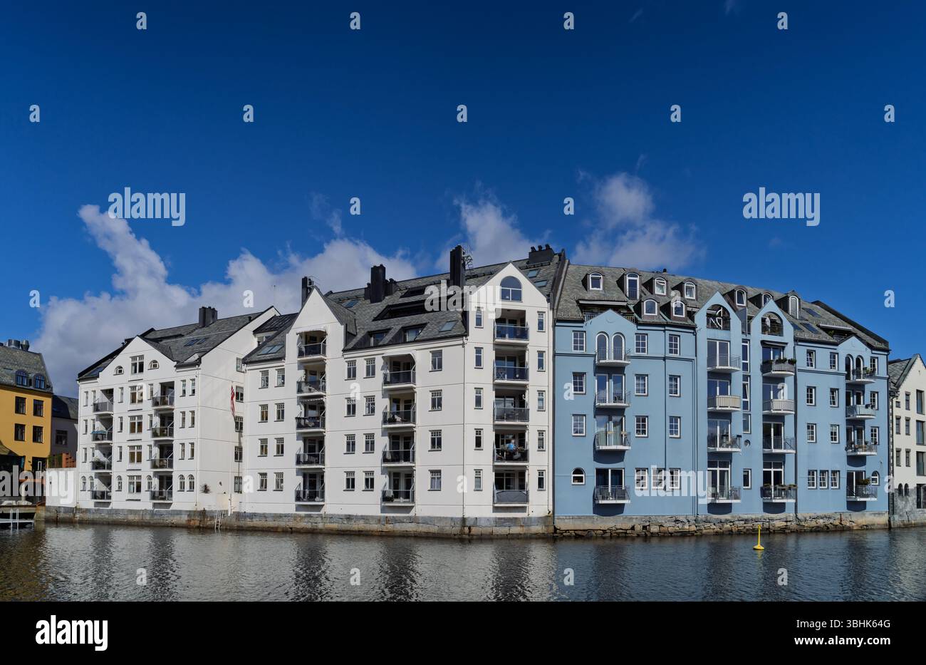 Incantevole vista di edifici colorati lungo un lungomare, sotto cieli azzurri. Le persone amano remare e kayak, creando un atmo vivace e vivace Foto Stock