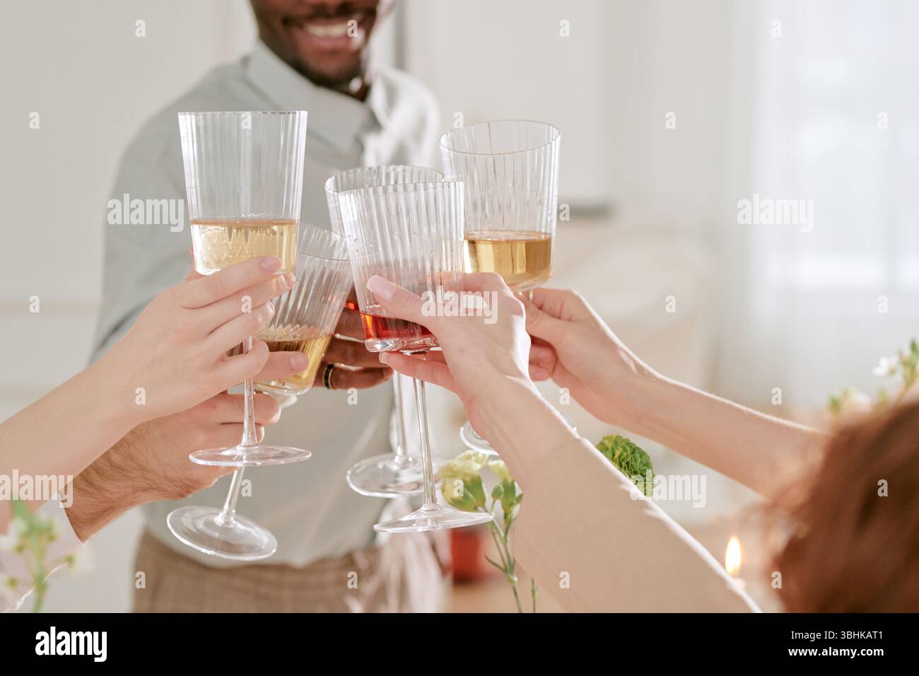 Gruppo di giovani adulti e persone di mezza età che si brunano durante la celebrazione del matrimonio, mani visibili che tengono vino e bicchieri da champagne durante il brindisi festivo Foto Stock