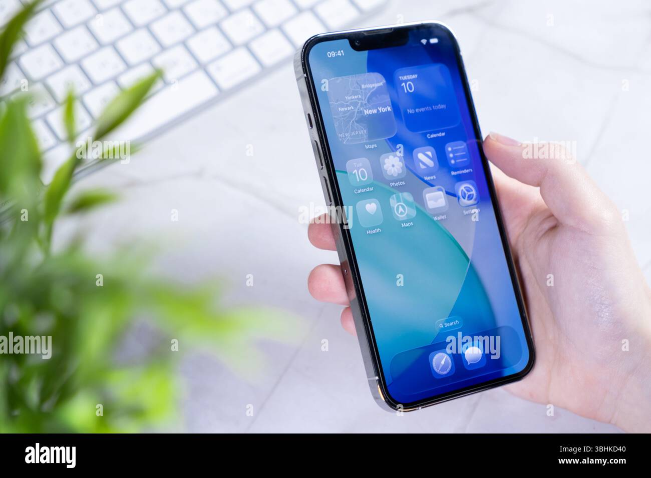 Poznan, Polonia - 10 giugno 2025: Mano che tiene in mano uno smartphone moderno che visualizza il nuovo sistema operativo iOS 26 con innovativo design dello schermo in vetro liquido Foto Stock
